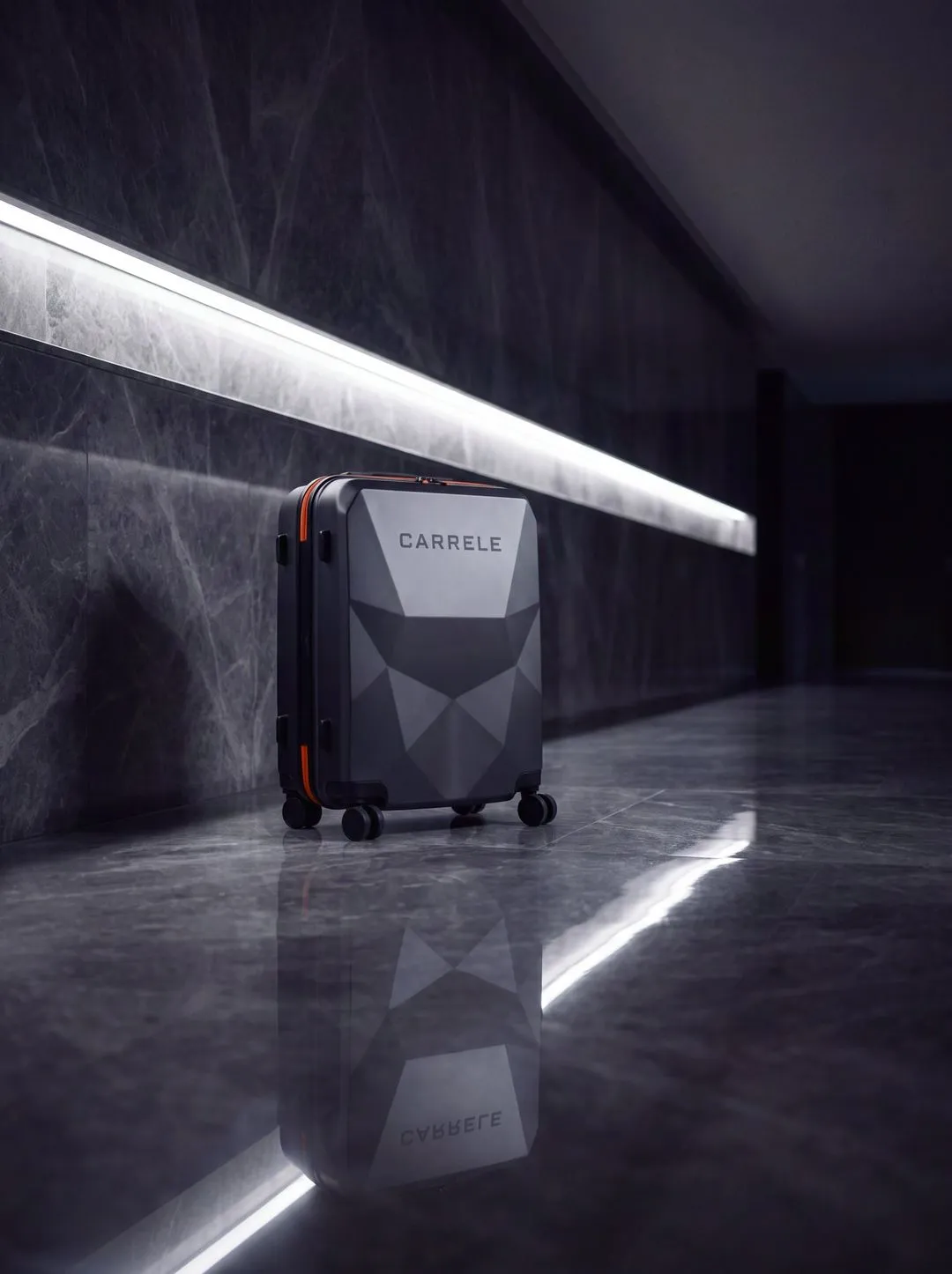Carrele suitcase in a dark marble corridor lit by a strip light, reflected in the polished floor.